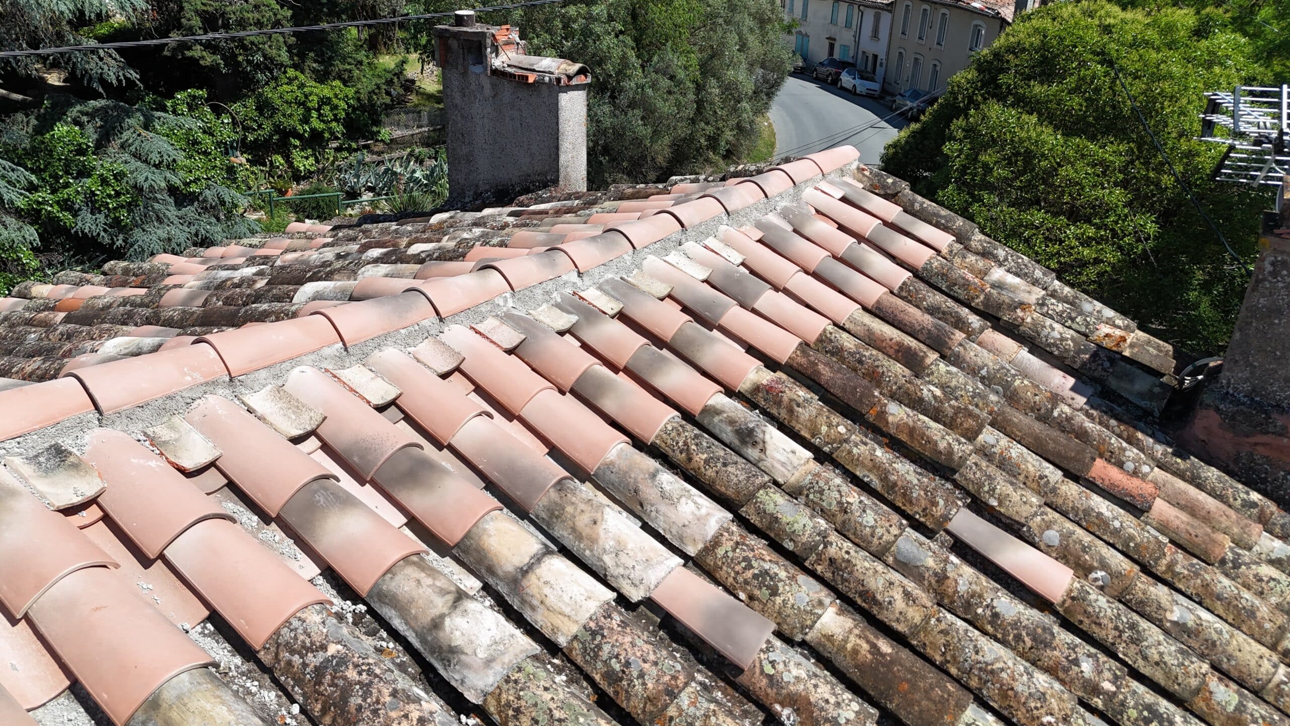 Toit de maison provençale avec tuiles canal en terre cuite, mêlant rénovation neuve et anciennes tuiles moussues.