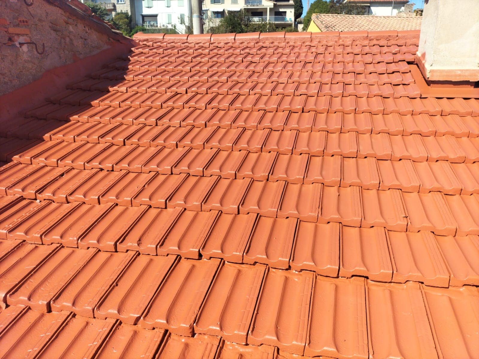 Toiture en tuiles de terre cuite orange vif, récemment rénovée pour une étanchéité optimale de la maison.